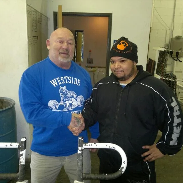 Pyhiinvaellusmatka 3 Kaksi miestä kättelee kuntosalilla.